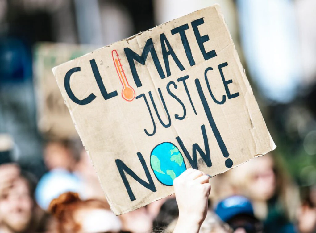 Foto: Demonstration, Person trägt Schild mit der Aufschrift "Climate Justice Now!"